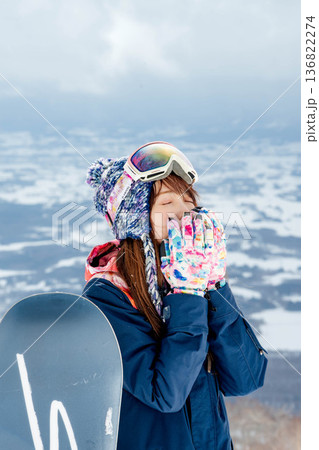 ゲレンデの頂上でスノーボードを楽しむ若い女性 136822274
