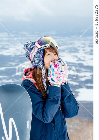 ゲレンデの頂上でスノーボードを楽しむ若い女性 136822275