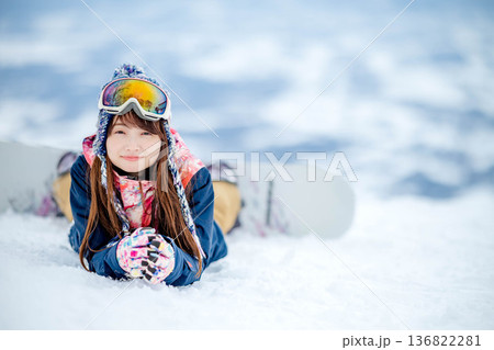 ゲレンデの頂上でスノーボードを楽しむ若い女性 136822281