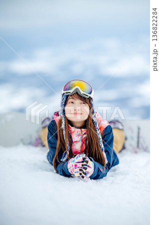 ゲレンデの頂上でスノーボードを楽しむ若い女性 136822284