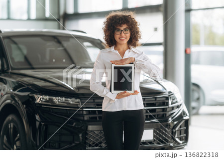 With digital tablet. Female employee is in the car retail shop With digital tablet. Female employee is in the car retail shop 136822318