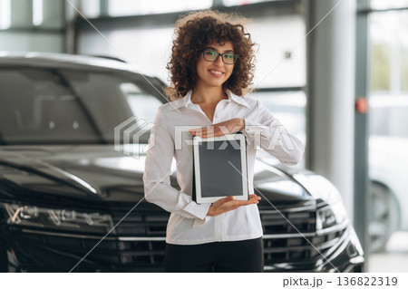With digital tablet. Female employee is in the car retail shop With digital tablet. Female employee is in the car retail shop 136822319