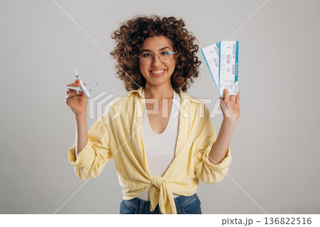 Two tickets and toy plane in hands. Beautiful woman is in the studio Two tickets and toy plane in hands. Beautiful woman is in the studio 136822516
