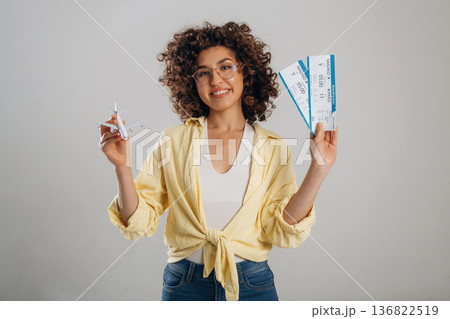 Two tickets and toy plane in hands. Beautiful woman is in the studio 136822519