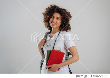 Backpack and educational material. Beautiful student doctor woman is in the studio Backpack and educational material. Beautiful student doctor woman is in the studio 136822688