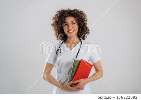 Educational material, notepads in hands. Beautiful student doctor woman is in the studio 136822692