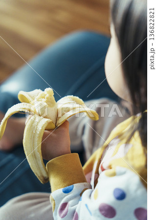 朝ごはんでバナナを食べる2歳児の風景 子育て・食育プレゼンやスライドショーに使える家族イメージ素材 136822821