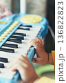 おもちゃピアノを弾く子どもの手元アップ 教育プレゼンやスライドショーに使える音楽イメージ背景素材 136822823
