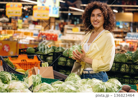 Cabbage is in hands. Gorgeous woman is in the grocery store Cabbage is in hands. Gorgeous woman is in the grocery store 136823464