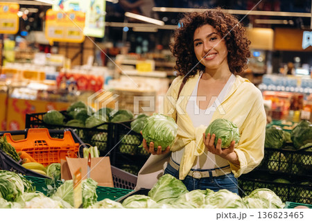 Cabbage is in hands. Gorgeous woman is in the grocery store Cabbage is in hands. Gorgeous woman is in the grocery store 136823465