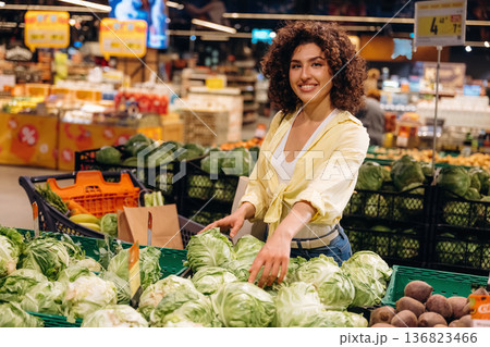 Cabbage is in hands. Gorgeous woman is in the grocery store Cabbage is in hands. Gorgeous woman is in the grocery store 136823466