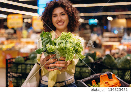Salad, vegetables. Gorgeous woman is in the grocery store 136823481