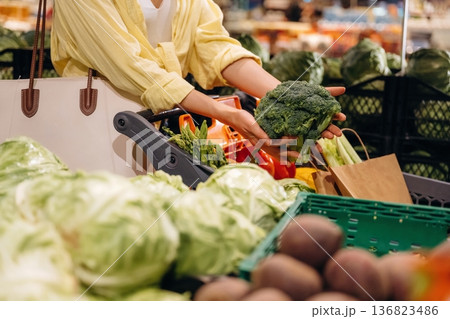 Holding cabbage. Close up view of woman that is choosing vegetables in the grocery store 136823486
