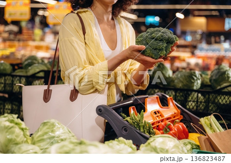 Holding cabbage. Close up view of woman that is choosing vegetables in the grocery store Holding cabbage. Close up view of woman that is choosing vegetables in the grocery store 136823487