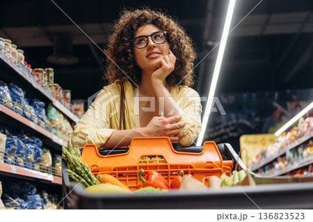 Leaning on the cart. Gorgeous woman is in the grocery store Leaning on the cart. Gorgeous woman is in the grocery store 136823523