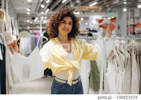 Fresh and new collection. Woman is shopping in the clothing store 136823574