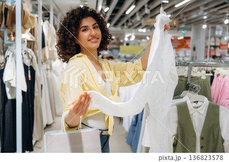 White shirt in hands. Woman is shopping in the clothing store 136823578