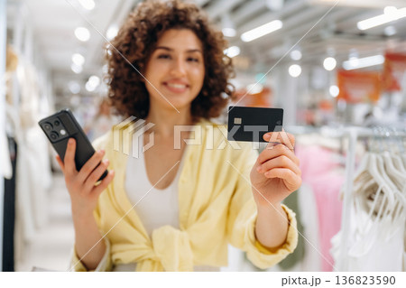 Payment by using credit card and phone. Woman is shopping in the clothing store Payment by using credit card and phone. Woman is shopping in the clothing store 136823590