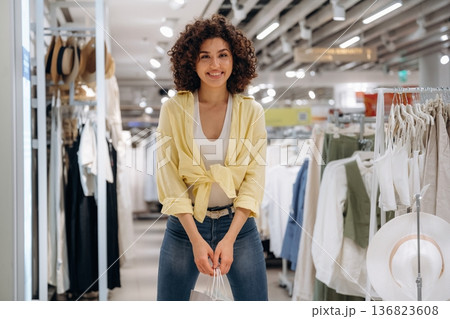 Shopping bags are in hands. Woman is shopping in the clothing store 136823608