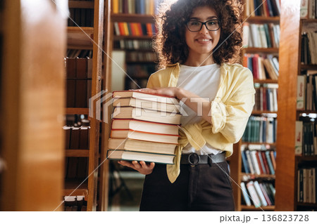 That's a lot of books in hands. Beautiful woman is in the library That's a lot of books in hands. Beautiful woman is in the library 136823728