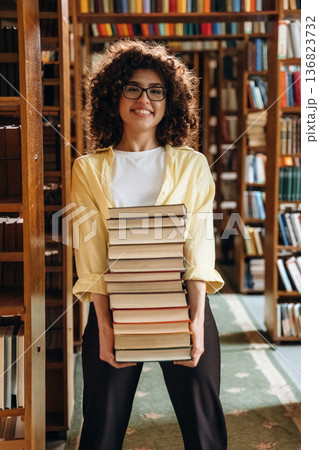 Standing and smiling. Beautiful woman is in the library Standing and smiling. Beautiful woman is in the library 136823732