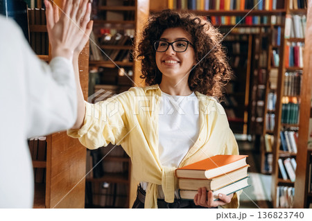 Two women are doing high five in the library Two women are doing high five in the library 136823740