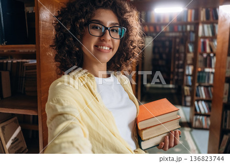 Making a selfie, smiling. Beautiful woman is in the library 136823744