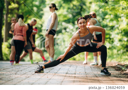 Flexibility, warm up exercise. Group of runners are together outdoors Flexibility, warm up exercise. Group of runners are together outdoors 136824059