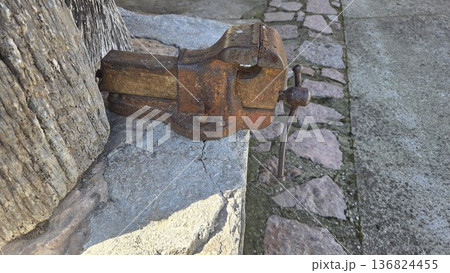 Old rustic bench vise mounted on stone wall in Asturias, Spain for historical metalworking concept Old rustic bench vise mounted on stone wall in Asturias, Spain for historical metalworking concept 136824455