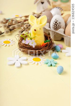 Easter spring holiday card. Playful bunny, painted eggs, willow branches, paper flowers, decorative elements on yellow background Easter spring holiday card. Playful bunny, painted eggs, willow branches, paper flowers, decorative elements on yellow background 136824505