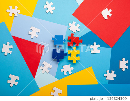 Autism Awareness Day design with colorful and white puzzle pieces on blue background, simple symbolic layout.  support and understanding, top view,  space for text. 136824509