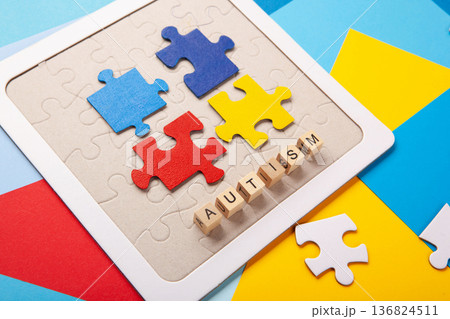 Autism Awareness Day design with colorful and white puzzle pieces on blue background, simple symbolic layout.  support and understanding 136824511