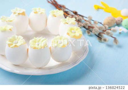 Easter spring holiday card. Playful bunny, painted eggs, willow branches, spring flowers, decorative elements on light blue background Easter spring holiday card. Playful bunny, painted eggs, willow branches, spring flowers, decorative elements on light blue background 136824522
