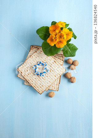 Passover holiday card with matzah, walnuts, yellow spring flowers on light blue background, gold and white accents, copy space 136824540