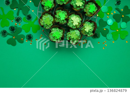 St. Patrick's Day vanilla cupcakes with green frosting and clover decorations on green background. Irish holiday dessert concept. Top view, copy space St. Patrick's Day vanilla cupcakes with green frosting and clover decorations on green background. Irish holiday dessert concept. Top view, copy space 136824879