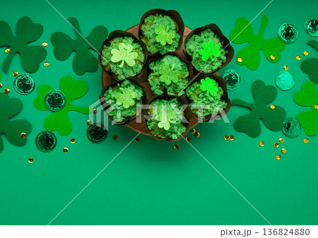 St. Patrick's Day cupcakes with green frosting and clover decorations on green background. Irish holiday dessert concept. Top view, copy space St. Patrick's Day cupcakes with green frosting and clover decorations on green background. Irish holiday dessert concept. Top view, copy space 136824880