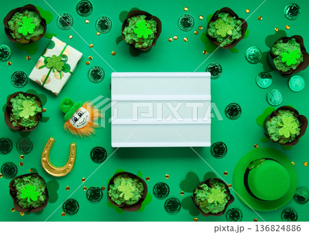St. Patrick's Day cupcakes with green frosting and clover decorations on green background. Irish holiday dessert concept. Top view, copy space 136824886