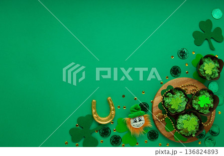 St. Patrick's Day vanilla cupcakes with green frosting and clover decorations on green background. Irish holiday dessert concept. Top view, copy space St. Patrick's Day vanilla cupcakes with green frosting and clover decorations on green background. Irish holiday dessert concept. Top view, copy space 136824893