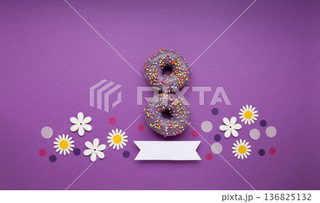 Give to Gain concept for International Women's Day, 8 march. Two purple doughnuts, red gift box and spring flowers, top view flat lay Give to Gain concept for International Women's Day, 8 march. Two purple doughnuts, red gift box and spring flowers, top view flat lay 136825132