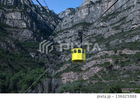 Iconic yellow Aeri de Montserrat cable car ascending the rugged jagged peaks of Montserrat mountain in Catalonia, Spain, under a clear blue sky Iconic yellow Aeri de Montserrat cable car ascending the rugged jagged peaks of Montserrat mountain in Catalonia, Spain, under a clear blue sky 136825988