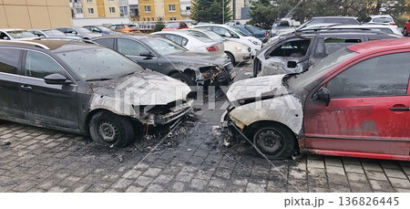 Front view of four fire-damaged cars with melted hoods and shattered windows 136826445