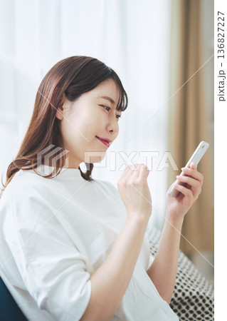 自宅のリビングでスマートフォンを操作する30代女性のライフスタイル 自宅のリビングでスマートフォンを操作する30代女性のライフスタイル 136827227