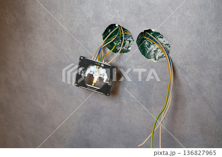 An electrical conduit box is built into the wall with wires sticking out as part of a home renovation  136827965