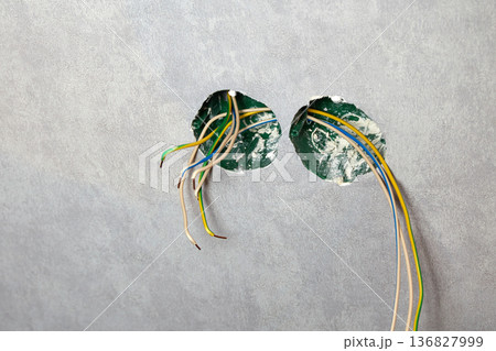 An electrical conduit box is built into the wall with wires sticking out as part of a home renovation  136827999