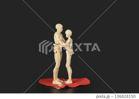 Conceptual image of two plastic mannequins hugging each other and stand on a large red heart with stitches, symbolizing reconciliation, healing a broken heart, and saving a relationship 136828150