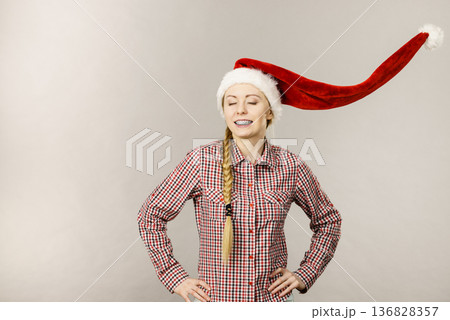 Positive girl wearing blowing santa claus hat Positive girl wearing blowing santa claus hat 136828357
