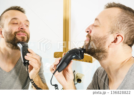 Man shaving trimming his beard Man shaving trimming his beard 136828822