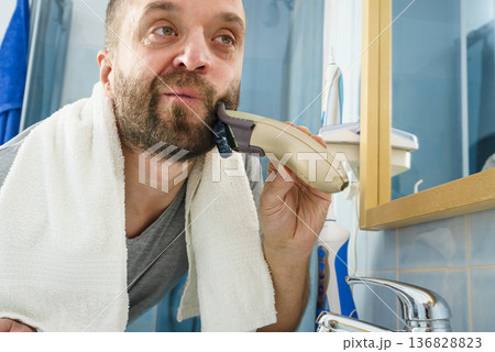 Man shaving trimming his beard Man shaving trimming his beard 136828823