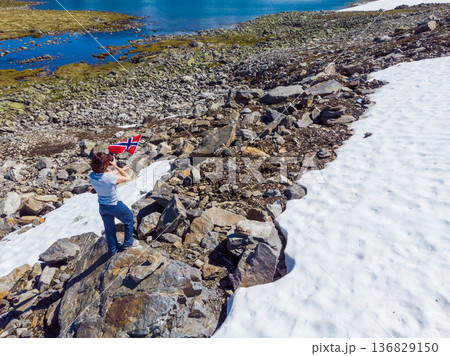 Tourist holds norwegian flag in mountains Tourist holds norwegian flag in mountains 136829150