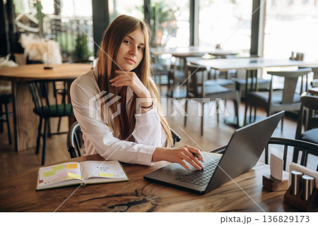 Student is with laptop. Young woman is in the cafe at daytime 136829173